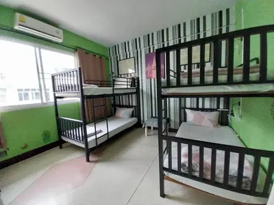a room with three bunk beds and a couch at Baan Nampetch Hostel in Bangkok