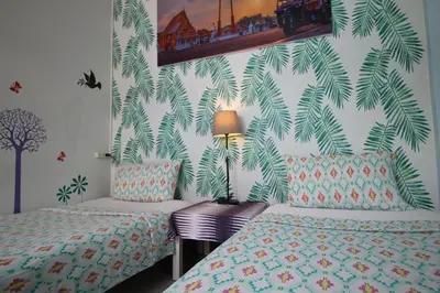 a bedroom with two beds and a wall with palm leaves at Baan Nampetch Hostel in Bangkok