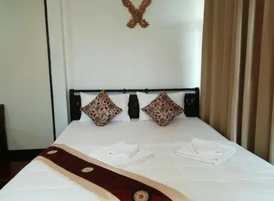 a bed with white sheets and pillows on it at Naturbliss Resort Village in Bangkok