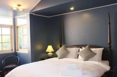 a bedroom with a large white bed with blue walls at Baan Ongkharak bed & breakfast in Bangkok