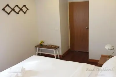 a bedroom with a bed and a table and a door at Baan Ongkharak bed & breakfast in Bangkok