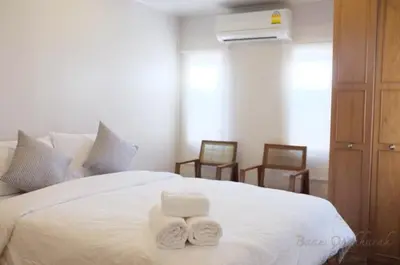 two towels on a white bed with two chairs at Baan Ongkharak bed & breakfast in Bangkok