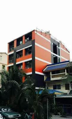 an orange and white building with palm trees in front of it at Popcorn House Ratchada in Bangkok