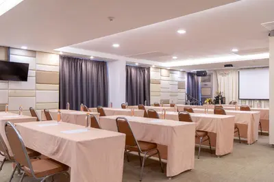 a conference room with tables and chairs and a screen at Leenova Hotel in Bangkok