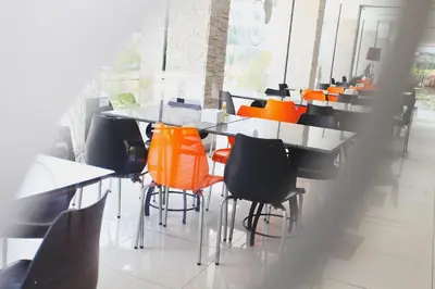 a group of tables and chairs with orange seats at Leenova Hotel in Bangkok