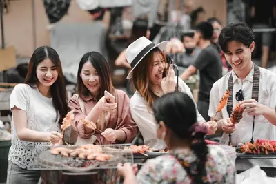 a group of people standing around a table eating food at Noursabah Boutique Bed Bangkok in Bangkok