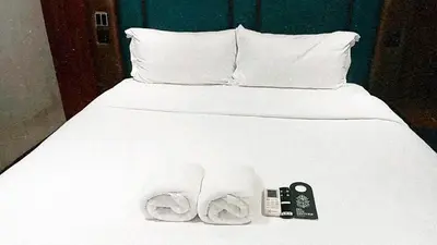 a bed with white sheets and a remote control on it at Narawad Boutique Hotel in Bangkok