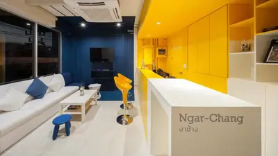 a living room with a white couch and yellow walls at BoB Hostel บ็อบโฮสเทล in Bangkok
