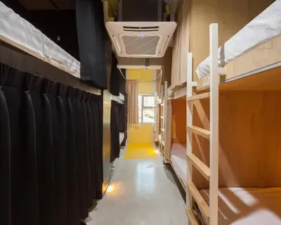 a hallway of a train with bunk beds and a yellow rug at BoB Hostel บ็อบโฮสเทล in Bangkok