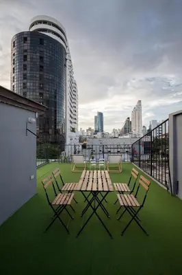 a patio with a table and chairs on a roof at BoB Hostel บ็อบโฮสเทล in Bangkok
