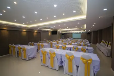 a large banquet hall with white tables with yellow bows at Villa Baron SHA PLUS in Nonthaburi