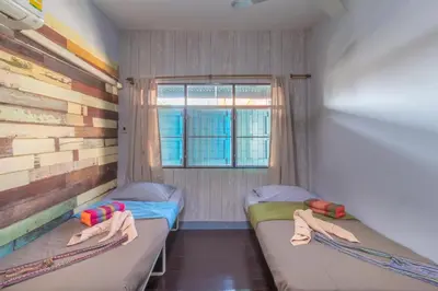 two beds in a small room with a window at Sor Vorapin Muay Thai Home in Bangkok