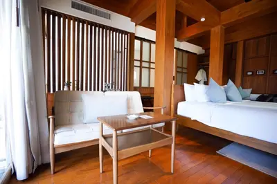 a bedroom with a bed and a chair and a table at Chann Bangkok Noi in Bangkok