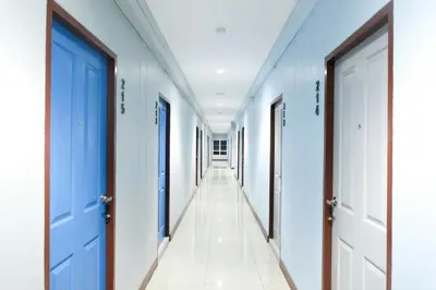 a corridor of a hospital with blue doors and white floors at โรงแรม เดอะริช ราชพฤกษ์ โฮเทล แอนด์ เรสซิเดนซ์ in Nonthaburi