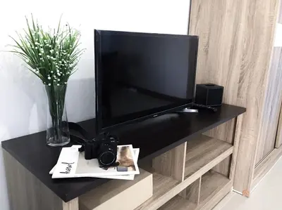 a television on a black stand in a room at โรงแรม เดอะริช ราชพฤกษ์ โฮเทล แอนด์ เรสซิเดนซ์ in Nonthaburi