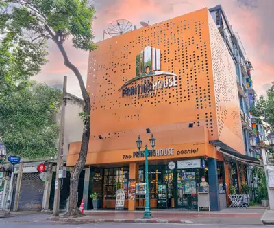 an orange building with a store on a street at The Printing House Poshtel in Bangkok