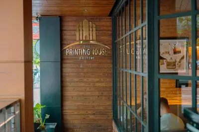 a door to a printing house with a man sitting inside at The Printing House Poshtel in Bangkok