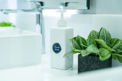a bathroom counter with a bottle of soap and a plant at The Printing House Poshtel in Bangkok