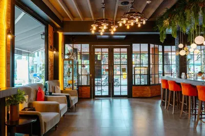 a restaurant with a bar with orange chairs and tables at The Printing House Poshtel in Bangkok