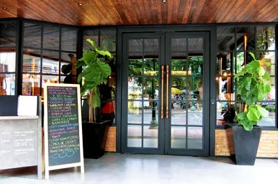 a restaurant with glass doors and a sign in front at The Printing House Poshtel in Bangkok