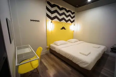 a bedroom with a large bed with a yellow headboard at BRB Hostel Bangkok Silom in Bangkok
