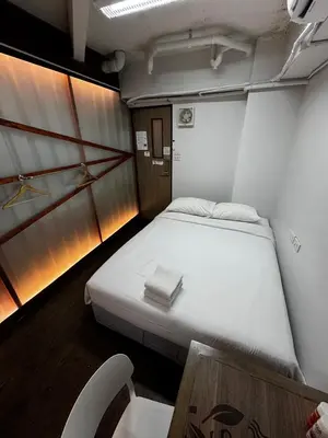 a small room with a bed and a table at Glur Central Pratunam in Bangkok