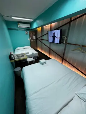 a hotel room with two beds and a tv at Glur Central Pratunam in Bangkok