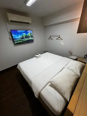 a bedroom with a large bed with a tv on the wall at Glur Central Pratunam in Bangkok