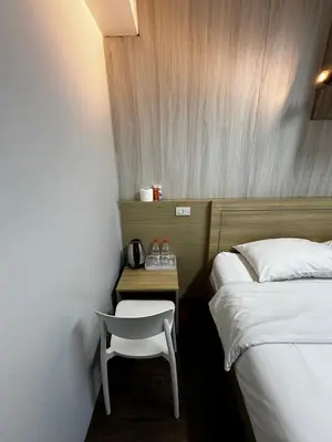a room with two beds and a chair next to a table at Glur Central Pratunam in Bangkok