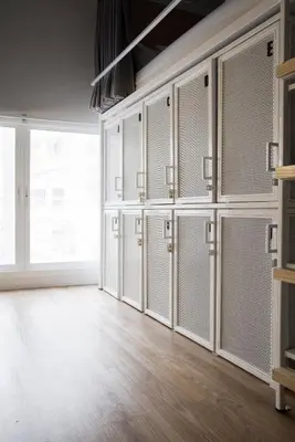 an empty locker room with white doors and wooden floors at Bed One Block Hostel in Bangkok