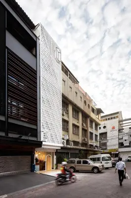 a person riding a motorcycle in front of a building at Bed One Block Hostel in Bangkok