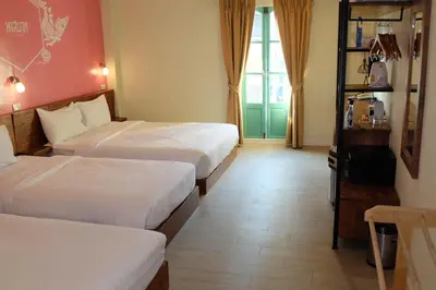 a hotel room with two beds and a window at Siri Poshtel Bangkok in Bangkok
