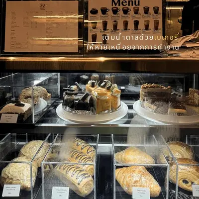 a display case with different types of cakes and pastries at Barn & Bed Hostel in Bangkok
