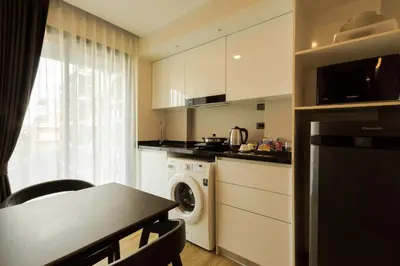 a kitchen with a washer and dryer and a table at Zensation The Residence in Bangkok