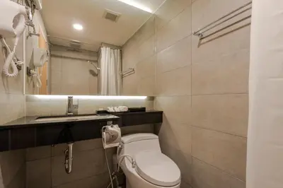 a bathroom with a toilet and a sink and a mirror at Zensation The Residence in Bangkok