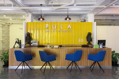 a yellow wall with a pula healthcare sign and four chairs at Pula Silom in Bangkok