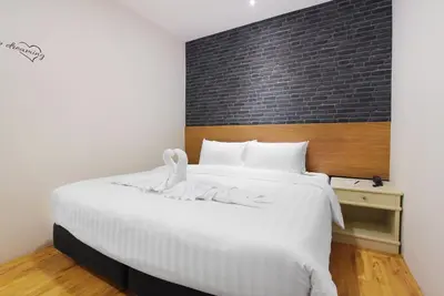 a bedroom with a large white bed with a brick wall at Pula Silom in Bangkok