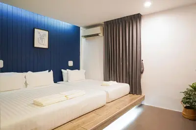 a bedroom with a large white bed with a blue wall at Marwin Space in Bangkok
