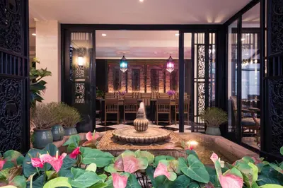 a lobby with a fountain in the middle of plants at Sara's Hotel in Bangkok
