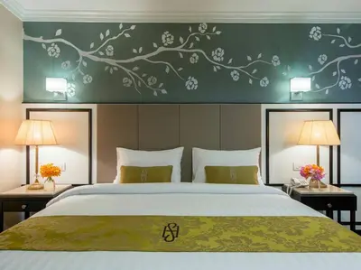a bedroom with a large bed with two tables and two lamps at Sara's Hotel in Bangkok