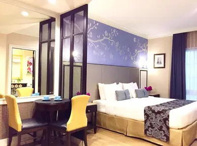 a bedroom with a bed and a table and chairs at Sara's Hotel in Bangkok