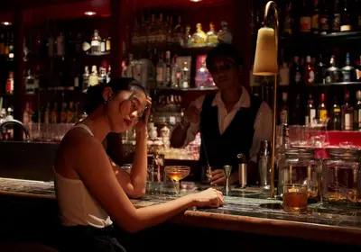 a woman sitting at a bar with a bartender at Josh Hotel in Bangkok