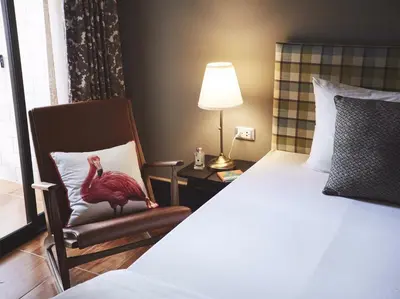 a bedroom with a bed and a chair with a bird on a pillow at Josh Hotel in Bangkok