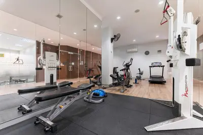 a gym with treadmills and ellipticals and a mirror at At 115 Hotel By Rompo in Bangkok