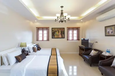 a bedroom with two beds and a television in it at The Lek Aree in Bangkok