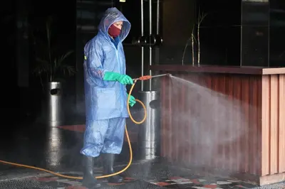 a person in a raincoat spraying a podium with a hose at Silom Space Hostel in Bangkok