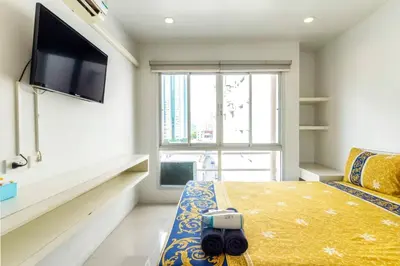 a bedroom with a large window and a tv on the wall at Right Place Sathorn in Bangkok