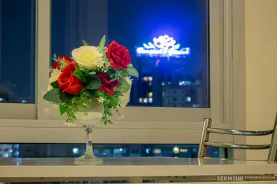a vase of flowers sitting on a table with a window at Right Place Sathorn in Bangkok