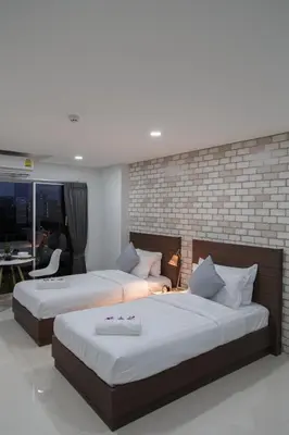 a bedroom with two beds and a brick wall at Q Space Residence in Bangkok