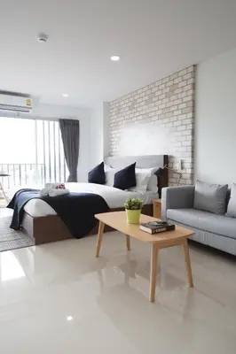 a bedroom with a bed and a table and a couch at Q Space Residence in Bangkok